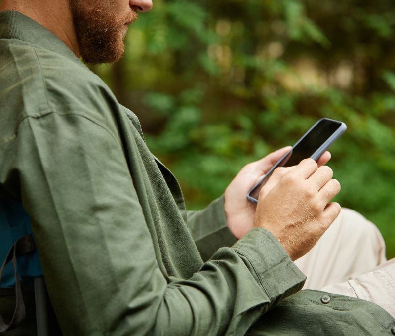 Mann mit Smartphone in grüner Jacke im Freien